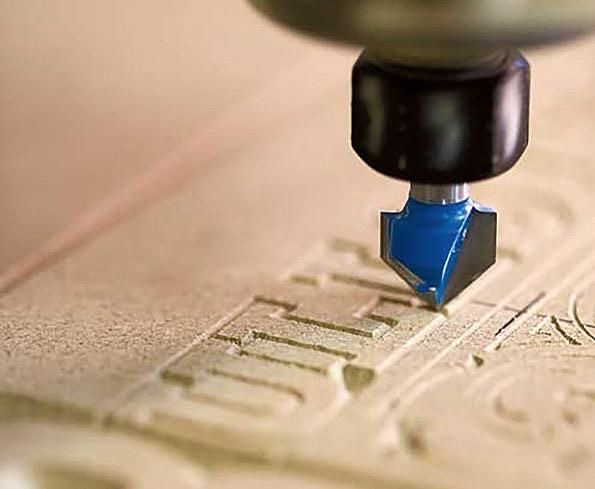 CNC machine engraving detailed text on a surface, showing precision and workforce skill development in manufacturing.