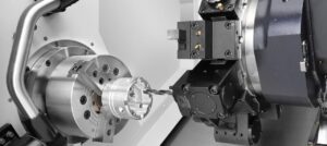 Close-up of a CNC lathe machine during high-precision part production with rotating chuck and drilling tool in operation.