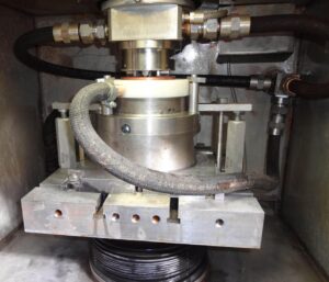 Close-up of electrochemical milling machine head with fluid connectors & precision tooling setup for metal shaping operations