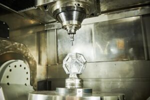 CNC milling machine working on a complex geometric metal part with high-precision spindle and rotary table setup.