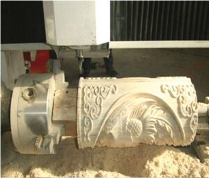 CNC router engraving detailed patterns and a rooster relief on a cylindrical wooden surface using rotary axis.